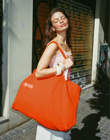 ; Stella wears the large Limited Edition Sunset Shopper in Hot Orange